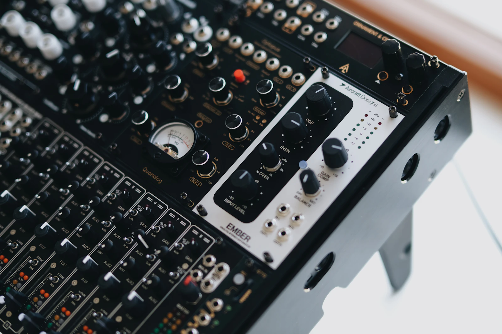 Close-up of an audio mixing console with rows of knobs, sliders and meters.