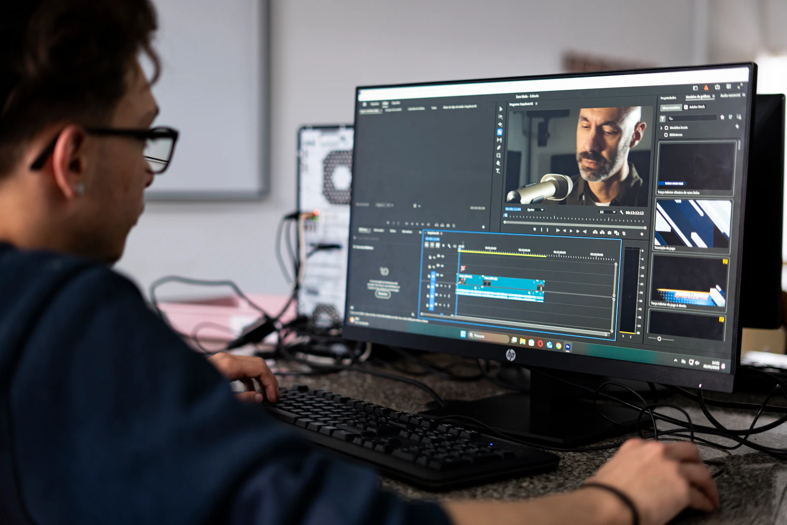 Editor checking video footage and an editing timeline on a desktop monitor.